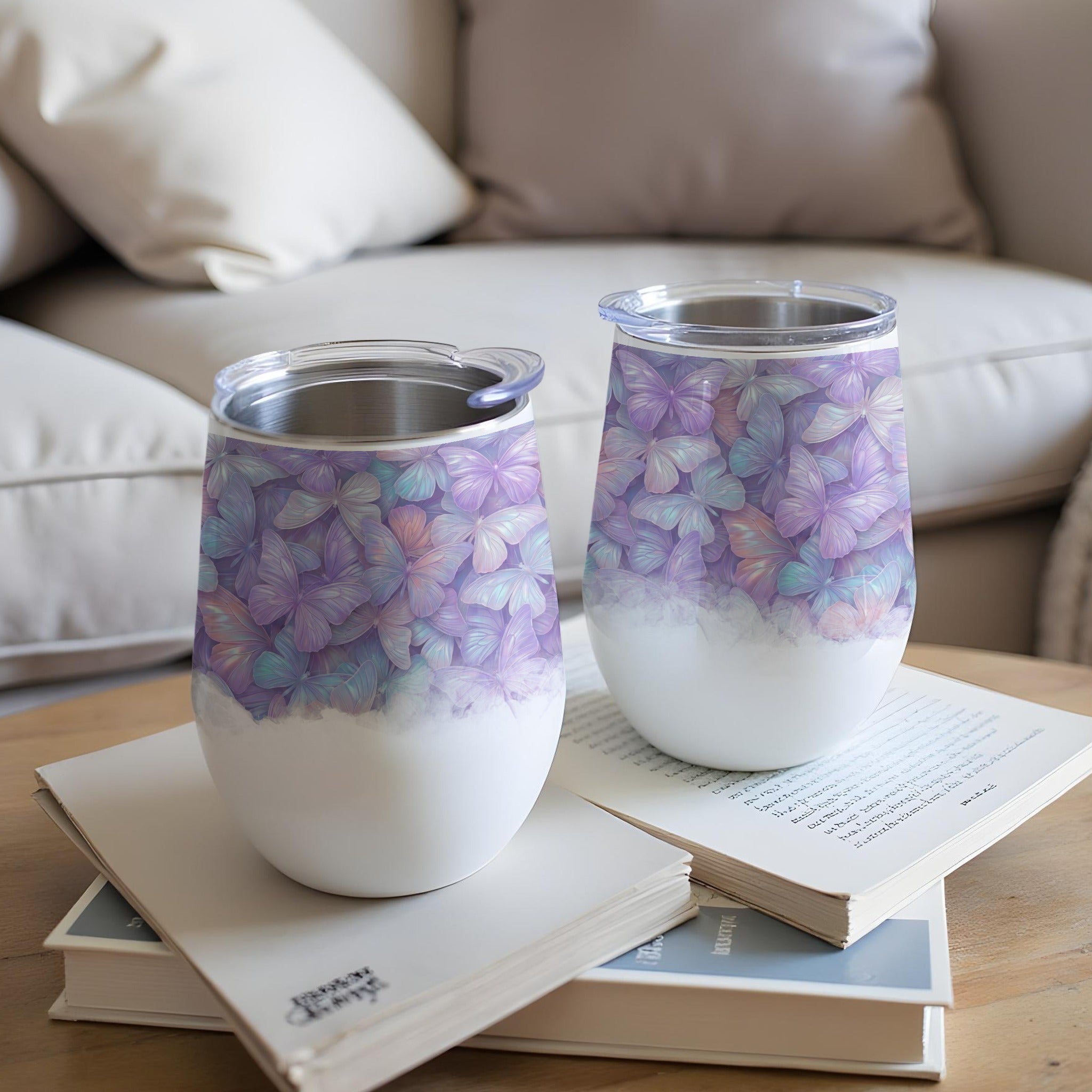 Two white wine tumblers with pastel butterfly pattern on a table.