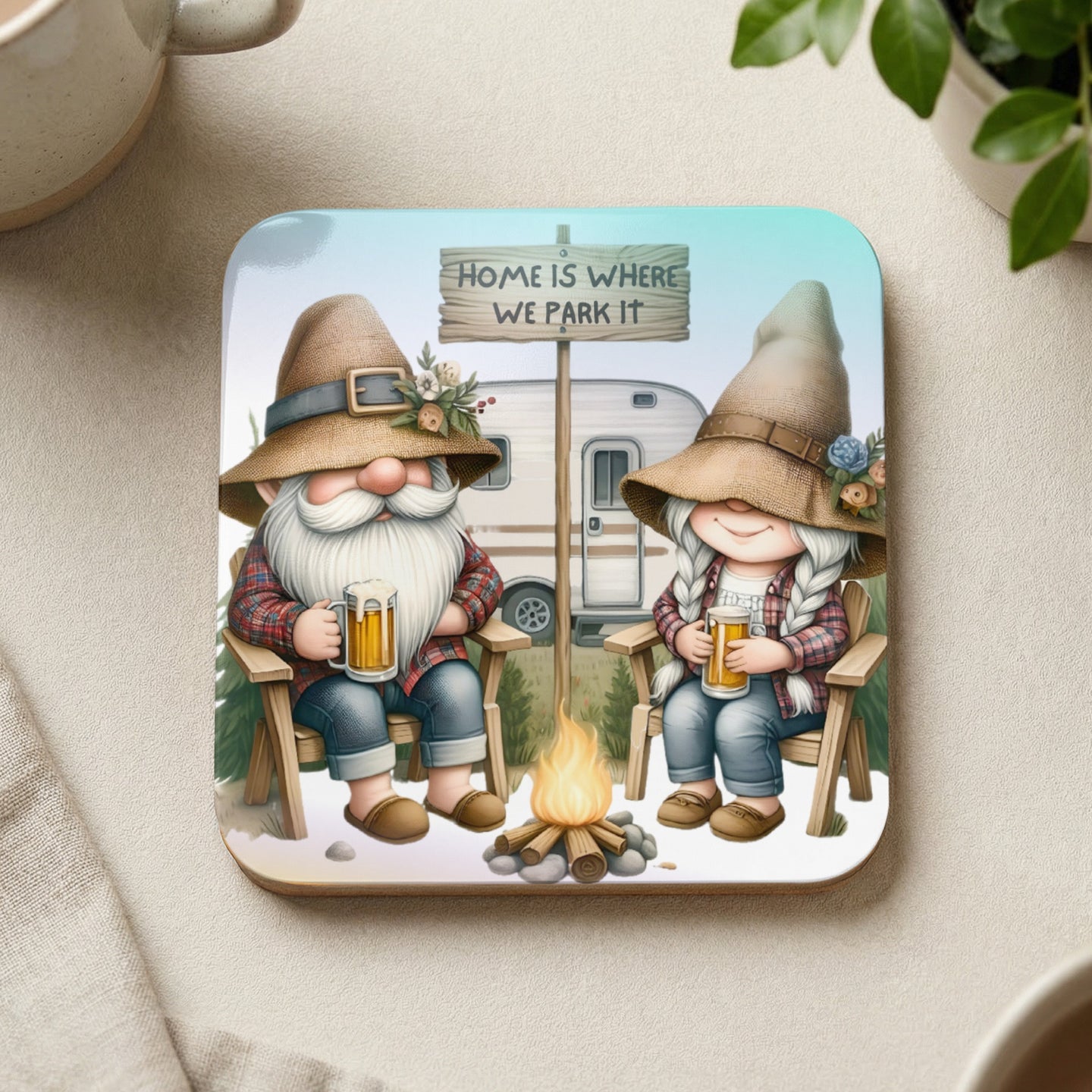 Gnomes with beer by campfire, camper trailer, text "HOME IS WHERE WE PARK IT".