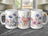 Three white mugs with watercolor floral designs, featuring purple, pink, and blue flowers.