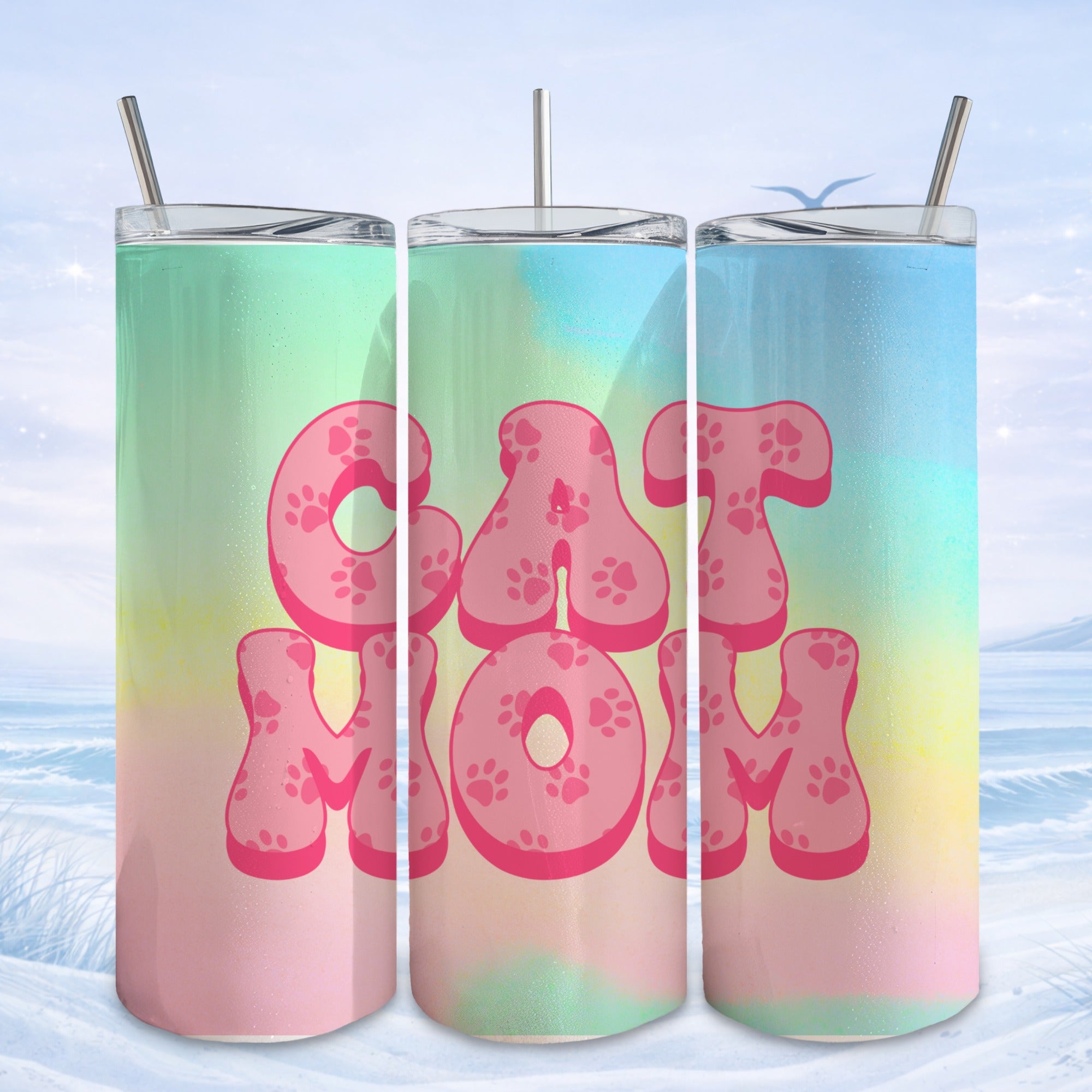 Pink paw print letters spell "CAT MOM" on a colorful gradient tumbler with a snowy background.