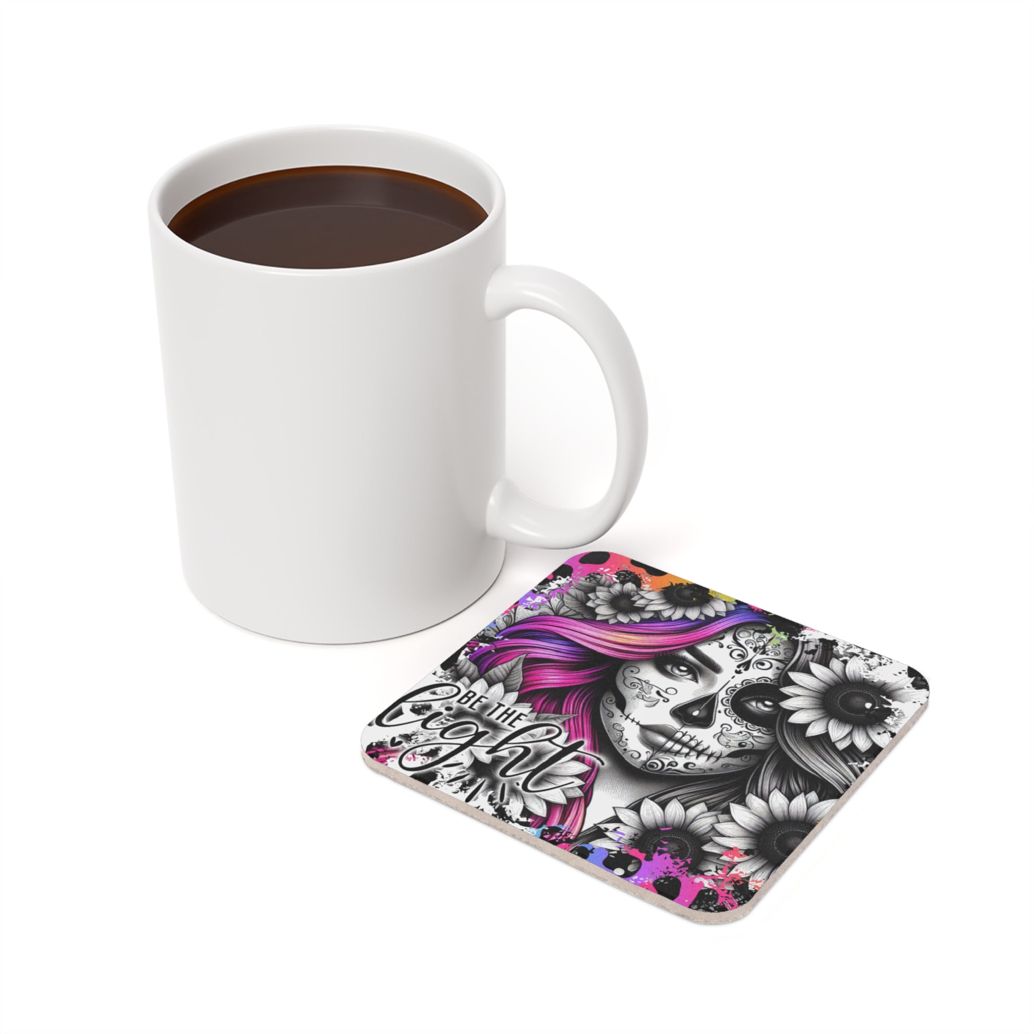 White mug of coffee next to a colorful Day of the Dead inspired coaster.