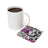 White mug of coffee next to a colorful Day of the Dead inspired coaster.