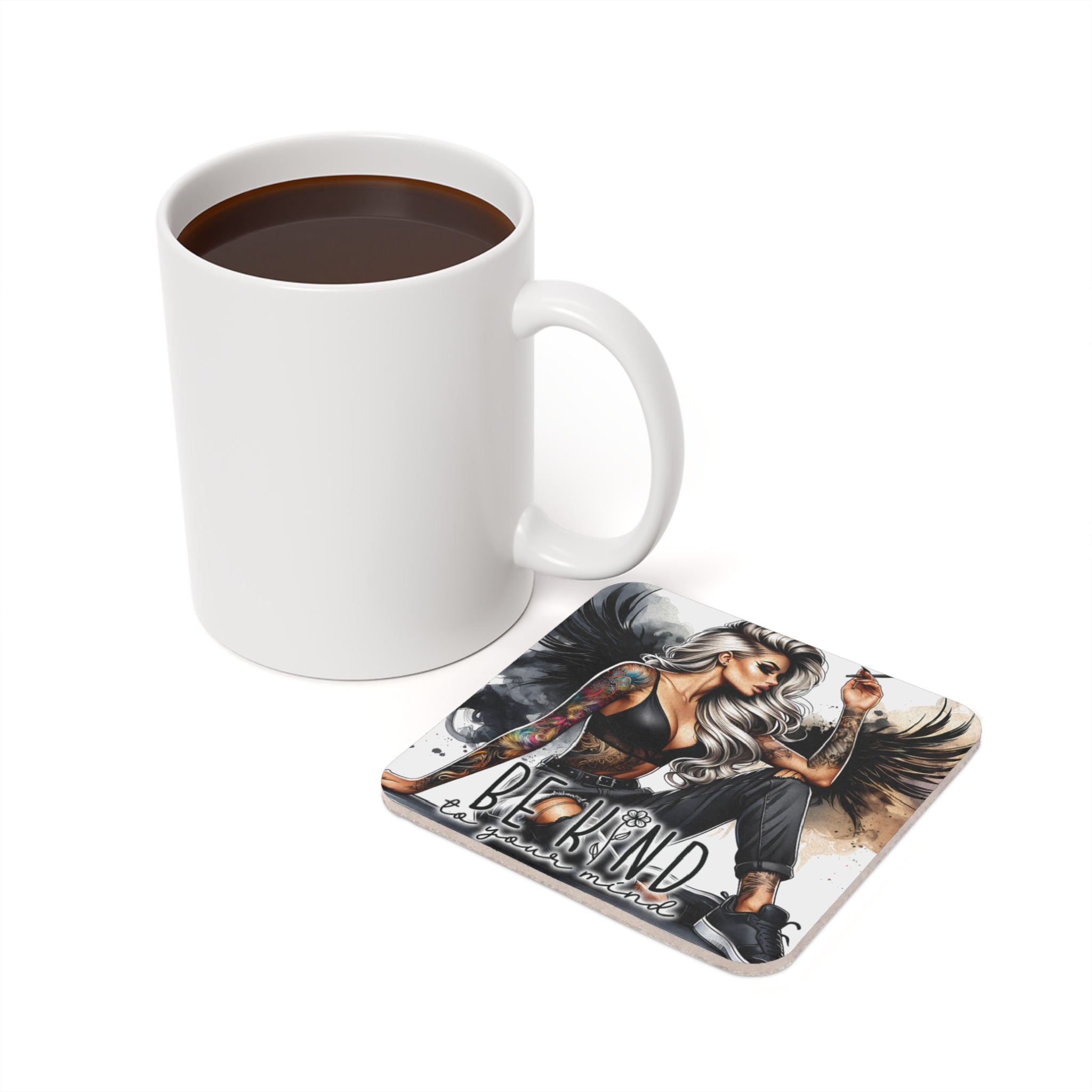 Mug of coffee next to a square coaster with woman and text "Be Kind".