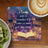 Open book with inspirational quote on a bookshelf background, with coffee and kiwi.