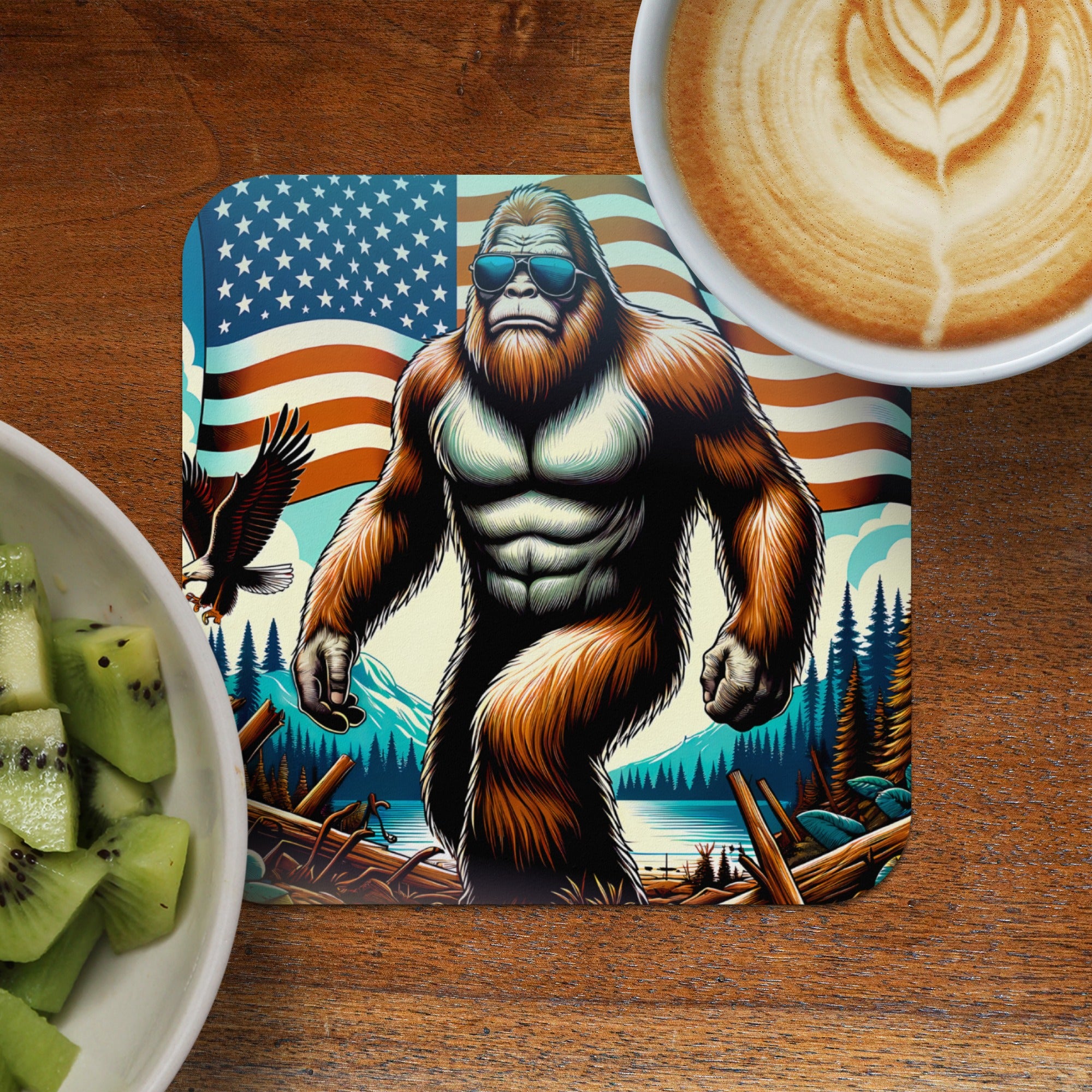 Bigfoot wearing sunglasses stands before an American flag and forest scene.