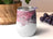 White tumbler with pink and purple abstract swirl design and glitter.