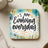 Coaster with "I AM Evolving everyday" text and floral dandelion design.