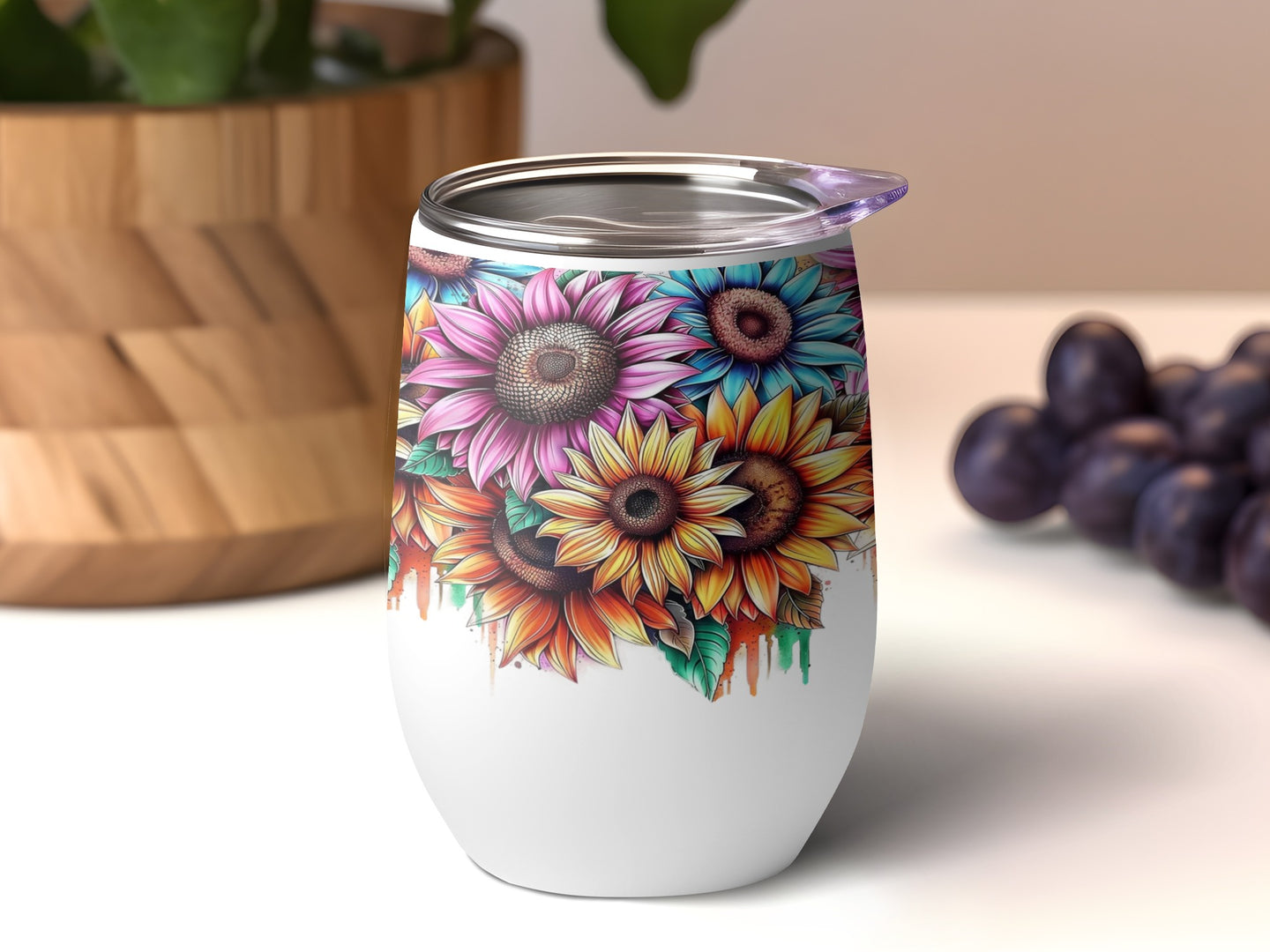 White tumbler with colorful sunflower design and purple grapes in background.