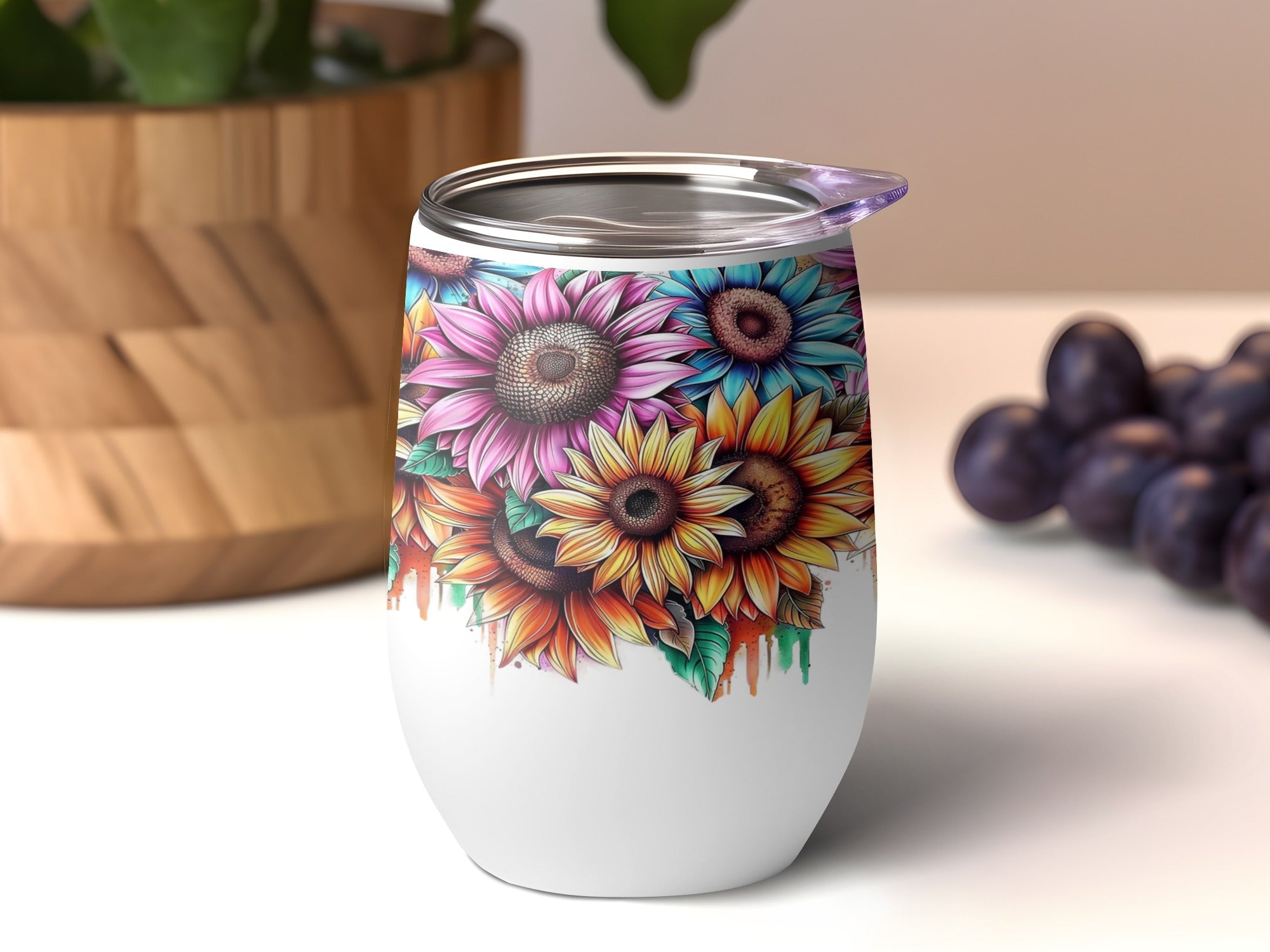 White tumbler with colorful sunflower design and purple grapes in background.