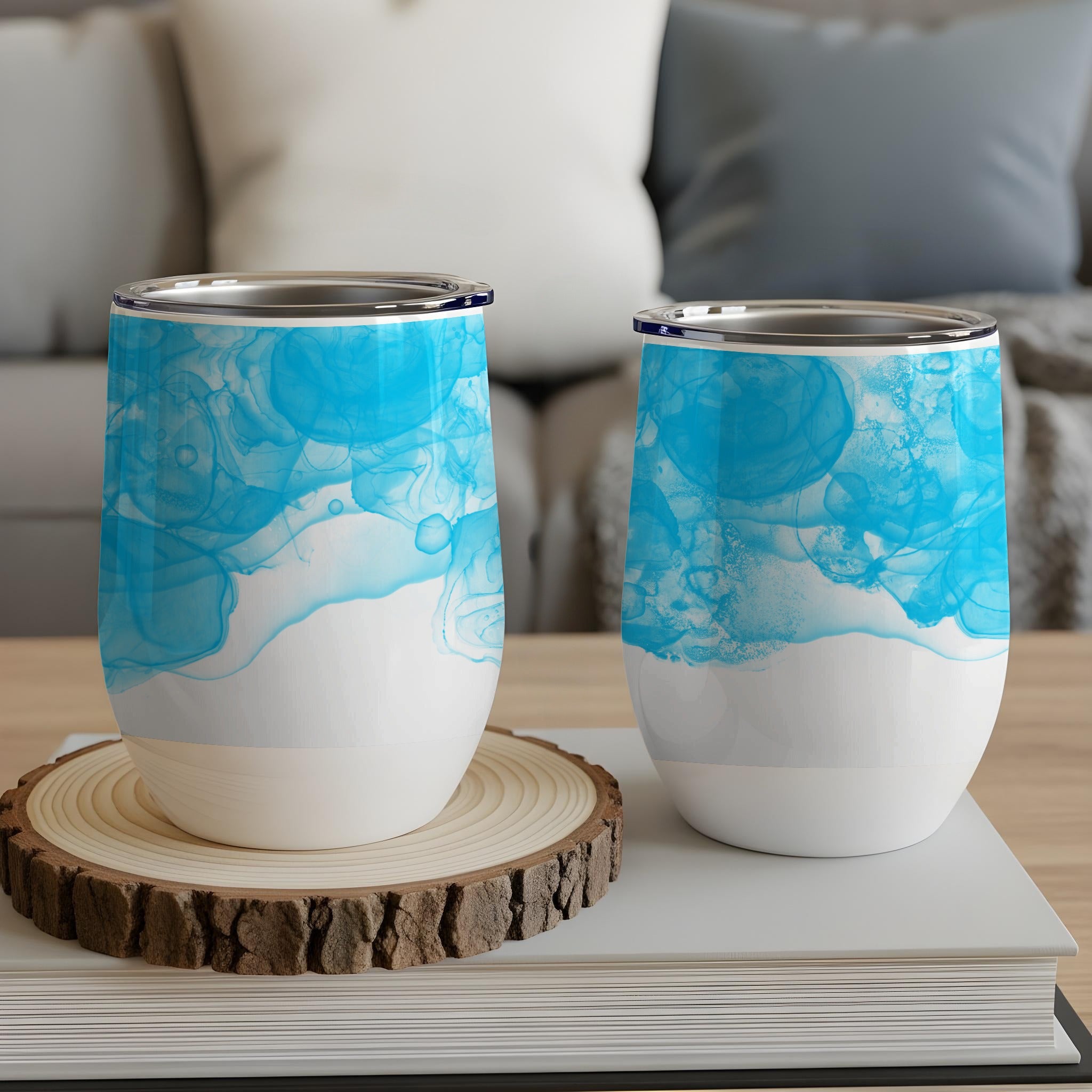 Two white stemless wine tumblers with blue abstract watercolor design.