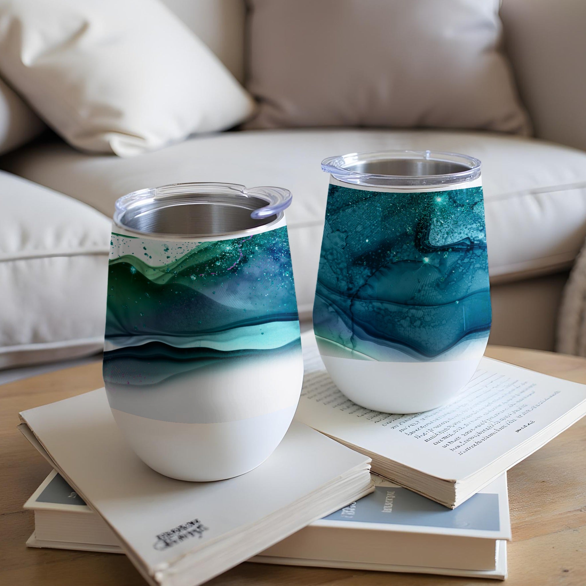 Two stemless wine tumblers with swirling teal, green, and white abstract art.