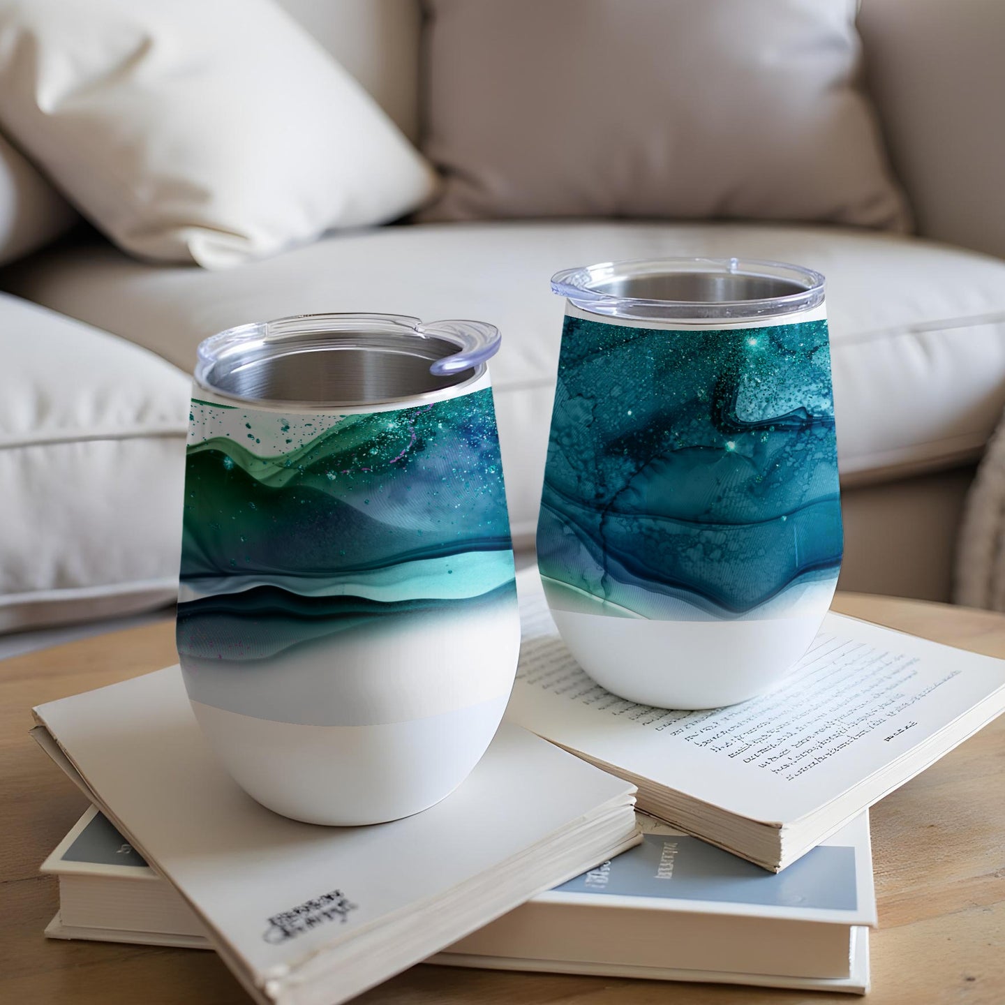 Two stemless wine tumblers with swirling teal, green, and white abstract art.