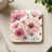 Pink cosmos flowers and a ladybug on a coaster with the text "Embrace Life".