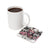 White mug of coffee next to a coaster with wolves and pink roses.
