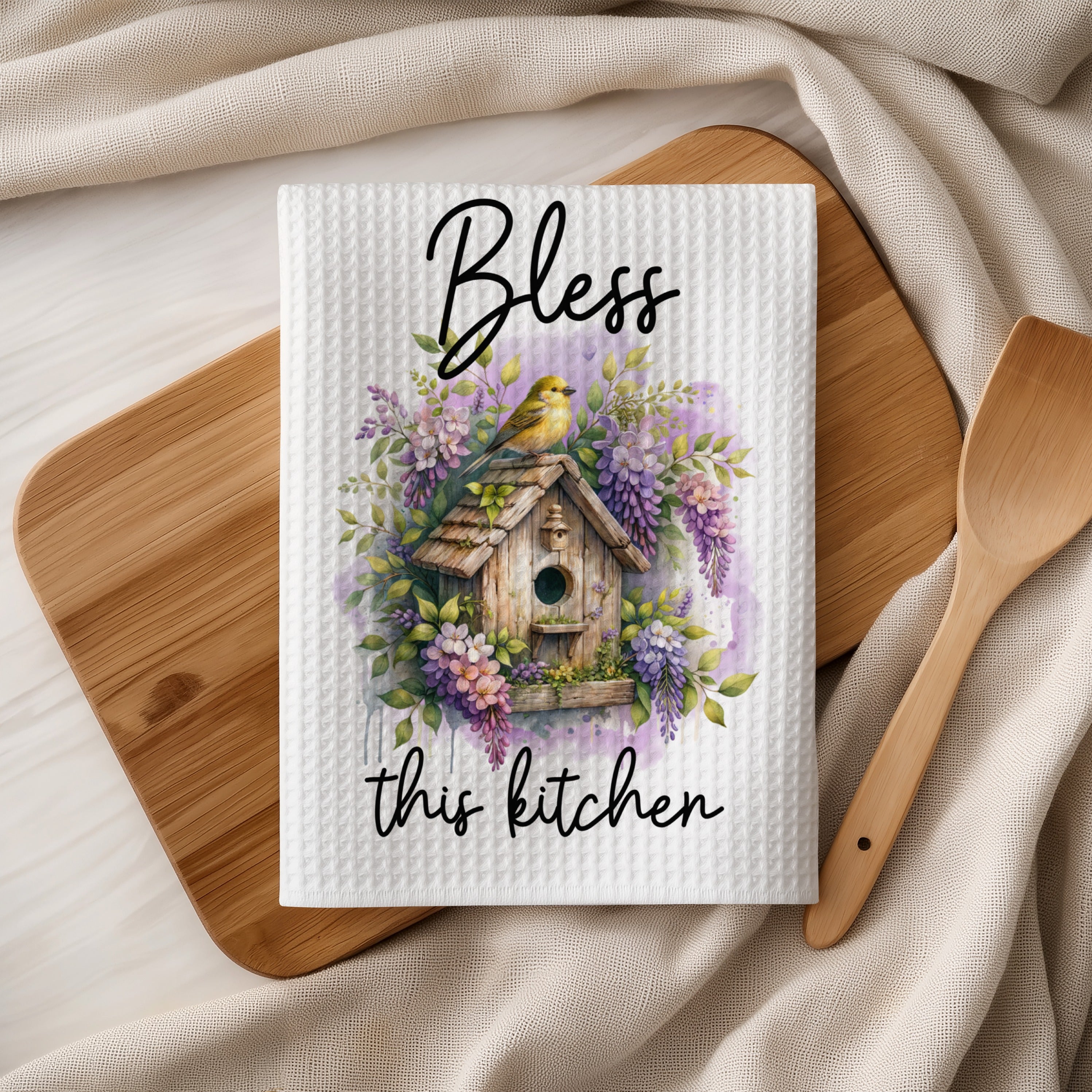Kitchen towel with birdhouse, flowers, and "Bless this kitchen" text.