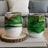 Two green marbled tumblers with gold glitter on a wooden coaster.