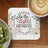 Square coaster with "Be the Light" and Matthew 5:14, framed by flowers.