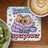 Coaster with cartoon book wrapped in blanket, text "Reading is my superpower".